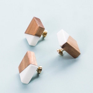 Puede incluir: Tres pomos de armario de madera y blanco en forma de diamante con herrajes de metal dorado.