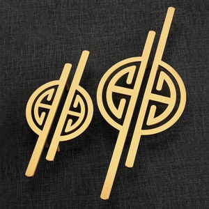 Pode incluir: Duas maçanetas de porta douradas com um design geométrico. As maçanetas são de metal e têm um visual elegante e moderno.