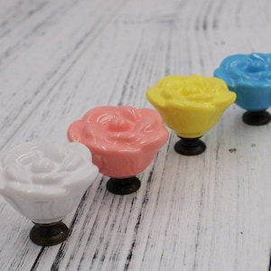Può includere: Quattro pomelli per cassetti in ceramica a forma di rosa, in bianco, rosa, giallo e blu.