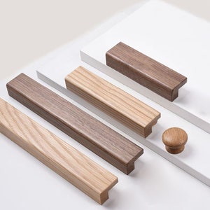 Peut inclure: Quatre poignées de tiroir en bois de différentes tailles, avec un bouton rond en bois. Les poignées sont en bois clair et foncé.