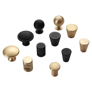Può includere: Assortimento di pomelli per armadi in finiture nere e dorate. I pomelli sono in metallo e hanno varie forme, tra cui rotonda, quadrata e cilindrica.