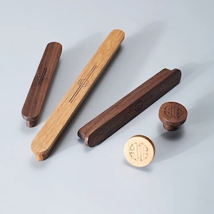 Peut inclure: Quatre boutons de cabinet en bois avec un motif chinois traditionnel. Deux boutons sont bruns et deux sont brun clair. Les boutons sont ronds et ont un motif en relief au centre.