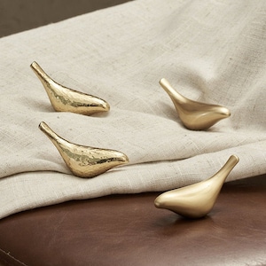 May include: Four gold bird-shaped hooks, two with a hammered finish and two with a smooth finish.