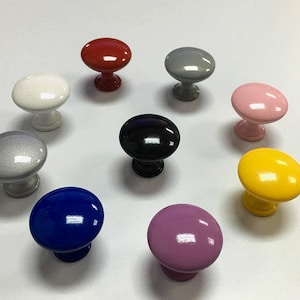 May include: Assortment of ten cabinet knobs in various colours, including red, white, black, grey, pink, yellow, blue, and purple. The knobs are round and have a smooth, glossy finish.