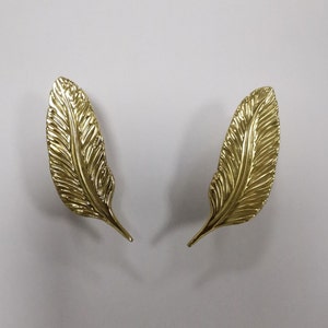 以下が含まれることがあります： 金色の羽根の形をしたイヤリングのペア