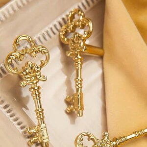 Può includere: Tre chiavi scheletriche ornate in tonalità dorata con disegni intricati. Le chiavi hanno un aspetto vintage e sarebbero un'ottima aggiunta a una collezione di arredamento per la casa.