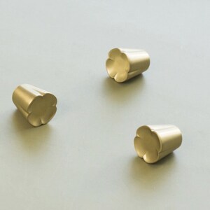 May include: Three gold-toned metal cabinet knobs with a flower-shaped design.
