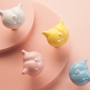 Può includere: Quattro pomelli per porte in ceramica a forma di animale in bianco, giallo, rosa e blu. I pomelli hanno la forma di un gatto con un corpo arrotondato e una piccola coda.