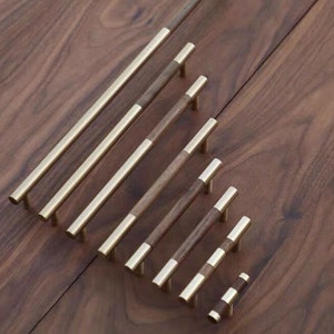 Peut inclure: Un ensemble de huit poignées de tiroir en laiton et en noyer de différentes tailles. Les poignées ont une finition en laiton brossé et un insert en bois de noyer.