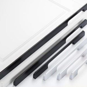 以下が含まれることがあります： 黒と銀の2つの仕上げで、6つのキャビネットプルがセットになっています。プルはすべて長方形で、角が丸く、中央にわずかなカーブがあります。