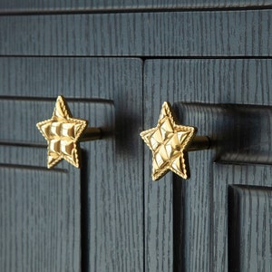 以下が含まれることがあります： 表面がテクスチャ加工された、金色の星型のキャビネットノブが2つ