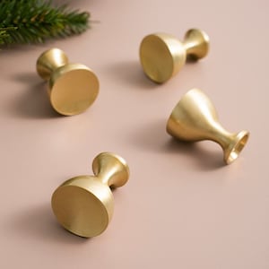 May include: Four gold-toned cabinet knobs with a round, slightly domed top and a flared base.
