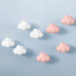 Peut inclure: Un ensemble de huit crochets en forme de nuage, quatre blancs et quatre roses. Les crochets sont conçus pour être montés sur un mur.