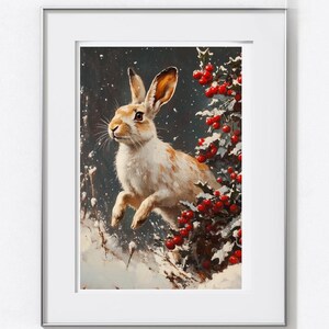 May include: A framed print depicting a white and tan rabbit in a snowy scene, near a holly bush with red berries. The artwork has a vintage style, suggesting a winter or Christmas theme. The rabbit is mid-leap.