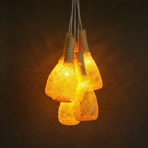 May include: A set of five woven pendant lights with a warm, yellow glow. The lights are made of natural materials and have a rustic, bohemian style.