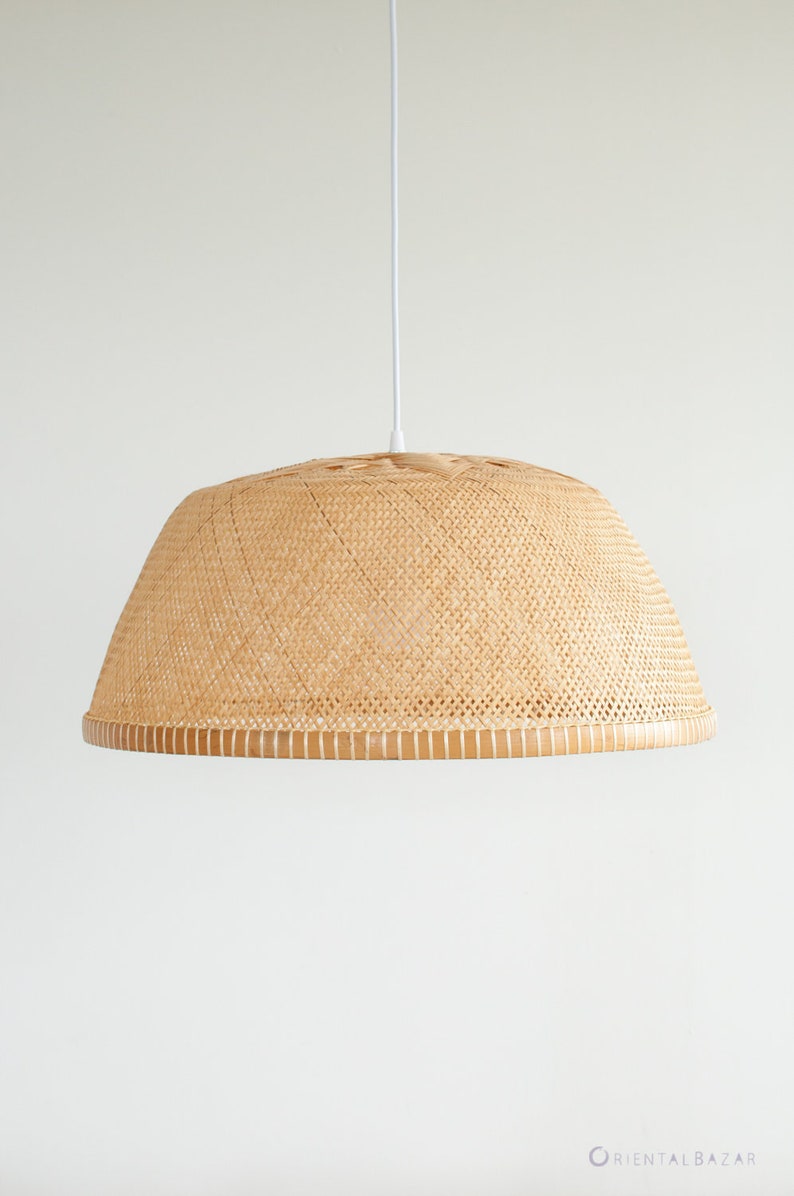 May include: A woven rattan pendant light fixture with a dome-shaped shade. The light fixture is hanging from a white cord against a white wall.