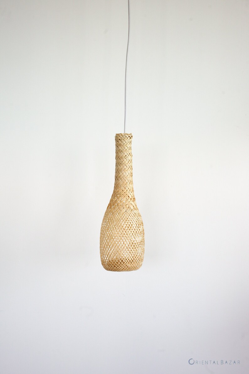 May include: A woven pendant light fixture with a natural beige color. The light fixture is shaped like a bottle and hangs from a white cord.