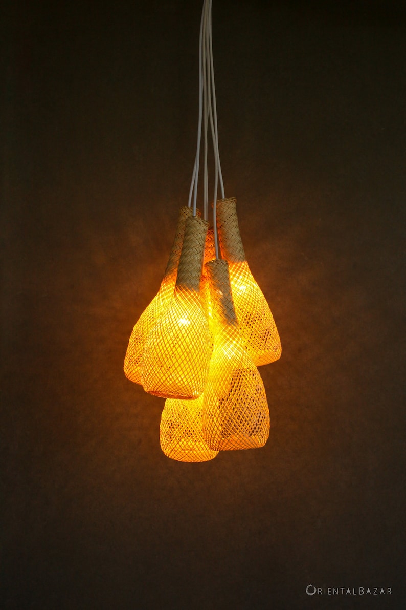May include: A set of five woven pendant lights with a warm, yellow glow. The lights are made of natural materials and have a rustic, bohemian style.