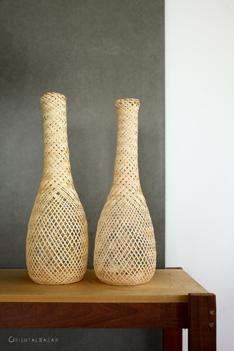 May include: Two woven wicker vases with a diamond pattern, sitting on a wooden table.