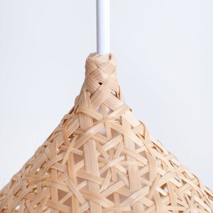 May include: A close-up of a woven bamboo pendant light fixture with a white cord.