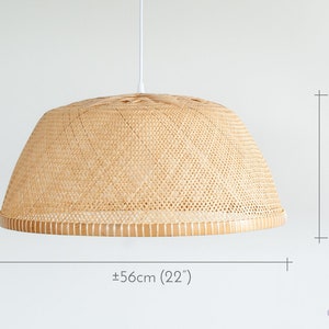 May include: A woven bamboo pendant light fixture with a white cord. The light fixture is 22 inches wide and 10 inches tall.