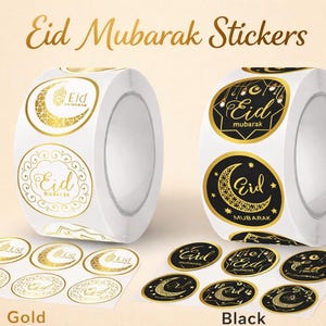 May include: Rolls of Eid Mubarak stickers in gold and black. The gold stickers feature a crescent moon and the word "Eid". The black stickers have a crescent moon and the word "Eid" in gold. The text "Eid Mubarak Stickers" is at the top.