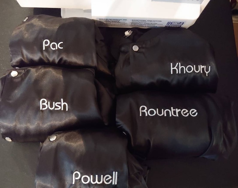Puede incluir: Cinco chaquetas de sat&eacute;n negro con nombres bordados en blanco: Pac, Bush, Khoury, Rountree y Powell.