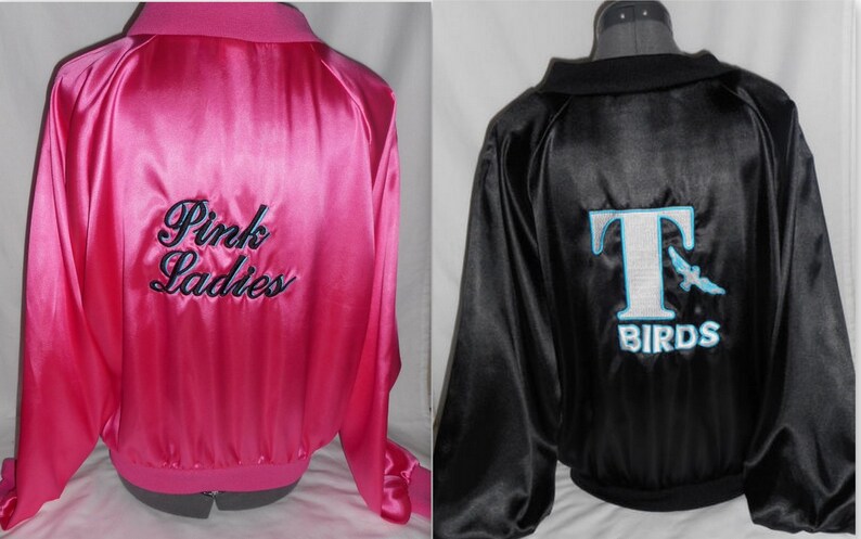 Puede incluir: Dos chaquetas de sat&eacute;n, una rosa con "Pink Ladies" bordado en la espalda, y una negra con un logotipo "T Birds" blanco con un p&aacute;jaro azul.
