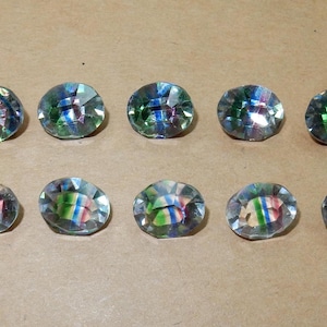 Peut inclure: Dix boutons ovales irisés avec un motif rayé multicolore. Les boutons sont un mélange de bleu, de vert et de rose.