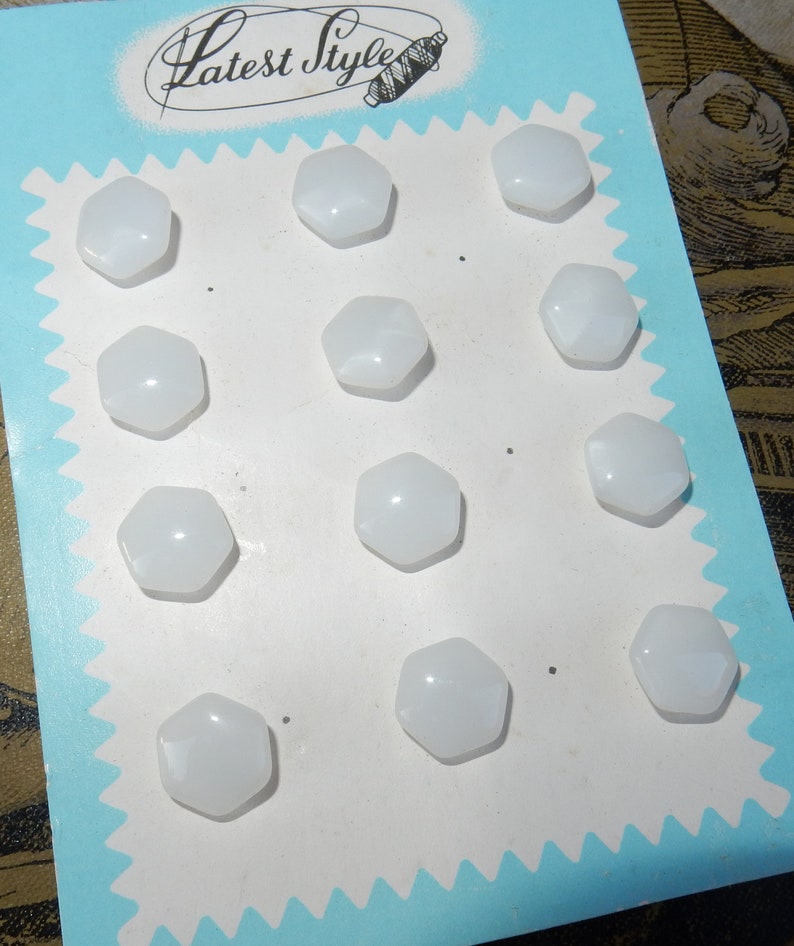 May include: A card with the text "Latest Style" printed on it. The card has a white background and a blue border. There are 12 white, hexagonal buttons arranged in rows on the card.