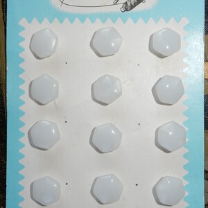 May include: A card with the text "Latest Style" printed on it. The card has 12 white, hexagonal buttons arranged in four rows of three buttons each.