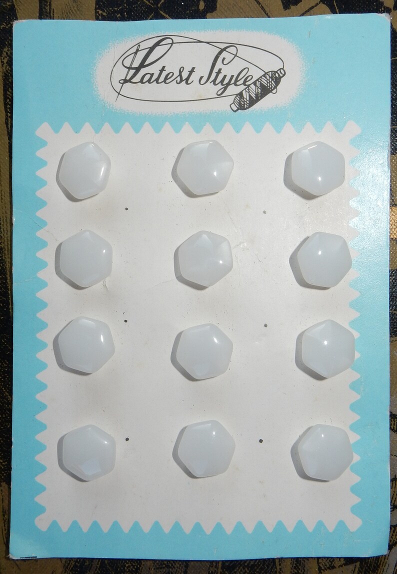 May include: A card with the text "Latest Style" printed on it. The card has 12 white, hexagonal buttons arranged in four rows of three buttons each.