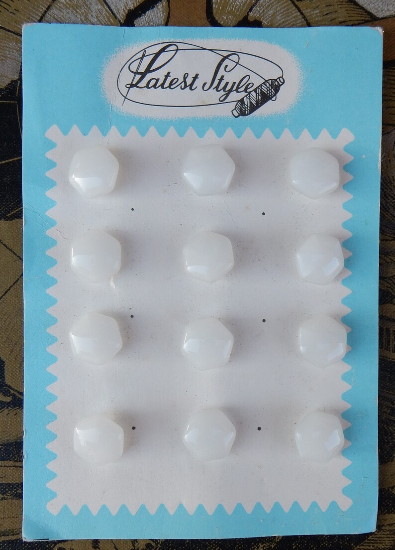May include: A card with the text "Latest Style" printed on it. The card has 12 white, hexagonal buttons attached to it.