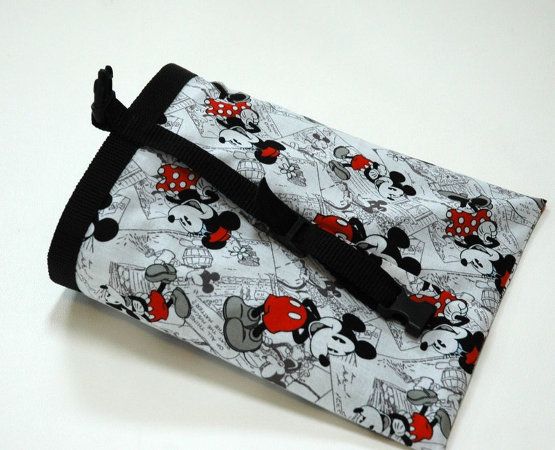May include: A black and white drawstring bag with a Mickey Mouse and Minnie Mouse print. The bag has a black adjustable strap with a buckle.