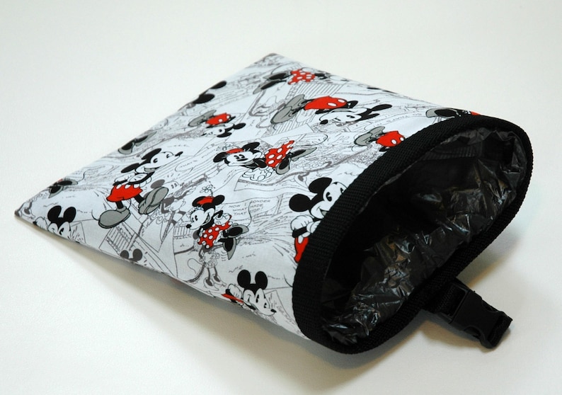 May include: A white fabric bag with a black trim and a black plastic clip. The bag is printed with a black and white cartoon image of Mickey Mouse and Minnie Mouse.