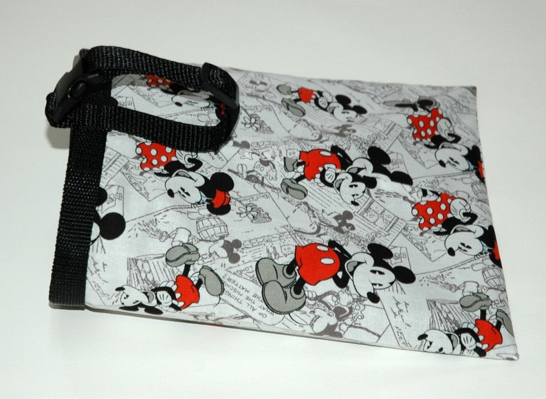 May include: A white fabric bag with a black strap and a repeating pattern of Mickey Mouse and Minnie Mouse in black and white with red accents.