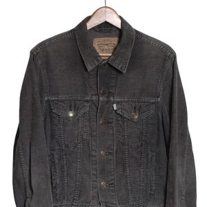 Op de afbeelding: Een donkergrijze corduroy jas met een klassiek ontwerp. De jas heeft een knoopsluiting, twee borstzakken en twee zijzakken. Het Levi Strauss & Co.-label is zichtbaar op de kraag.