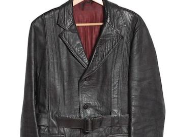 Peut inclure: Une veste en cuir noire avec une ceinture, deux poches et une fermeture à bouton.