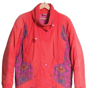 Puede incluir: Una chaqueta acolchada vintage roja y rosa con un patrón geométrico en las mangas y un cuello alto.