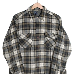May include: A long-sleeved plaid shirt in green, white and black. The shirt has a button-down collar and two chest pockets.