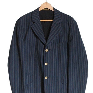 Puede incluir: Una chaqueta azul oscuro a rayas con cuatro botones dorados. La chaqueta tiene un estilo clásico y está hecha de una tela suave y cómoda.