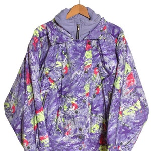 May include: A purple, green, and red patterned ski jacket with a zipper closure and snap buttons. The jacket has a hood and a printed design with text that reads "trends and articles about contemporary design".