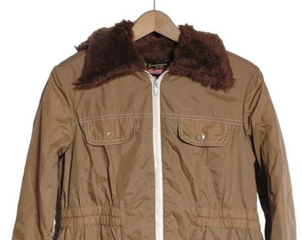 Könnte beinhalten: Eine braune Jacke mit einem Kunstfellkragen und einem weißen Reißverschluss. Die Jacke hat zwei große Taschen vorne und einen Kordelzug in der Taille.