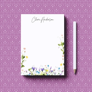 May include: A white notepad with the name "Clare Anderson" printed at the top. The notepad has a floral border with watercolor flowers in shades of blue, yellow, and pink.