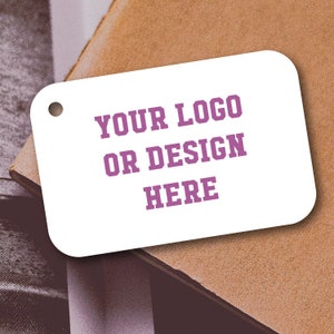 May include: White rectangular tag with rounded corners and a hole at the top. The tag has the text "YOUR LOGO OR DESIGN HERE" in purple.