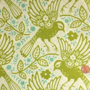 Może przedstawiać: Materiał z powtarzającym się wzorem zielonych ptaków z kwiatowymi akcentami, liśćmi i kwiatami na kremowym tle. Ptaki są przedstawione ze skrzydłami w locie. Zawiera jasnoniebieskie akcenty.
