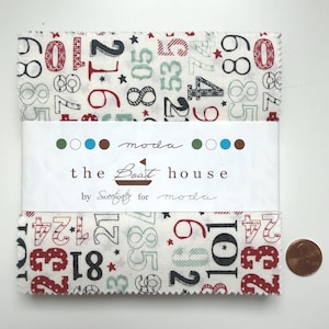 Może przedstawiać: Stos kwadratów materiału z białym tłem, z liczbami w kolorze czerwonym, czarnym i zielonym. Materiał jest owinięty etykietą z napisem "the Boat house" i "moda". Obok materiału znajduje się moneta.