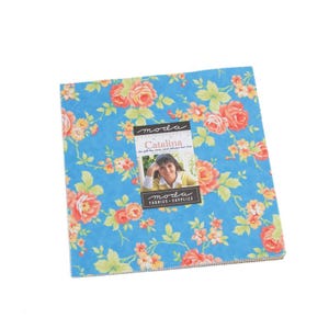 Może przedstawiać: Stos kwadratowych kawałków materiału z kwiatowym wzorem w odcieniach pomarańczu, żółci i zieleni na jasnoniebieskim tle. Mała etykieta głosi "Moda Catalina" ze zdjęciem kobiety.