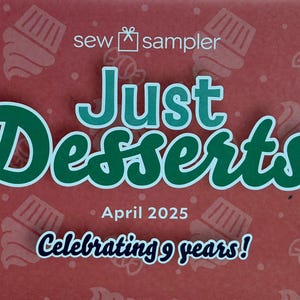 Può includere: Una scatola rettangolare rossa con un motivo ripetuto di icone bianche di cupcake e caramelle. Il testo recita sew sampler, Just Desserts, April 2025 e Celebrating 9 years! Le scritte sono in tonalità di verde e blu scuro con bordi bianchi.