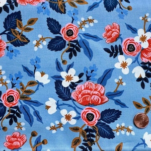 Może przedstawiać: Niebieski materiał z kwiatowym wzorem. Kwiaty są czerwone, różowe i białe z zielonymi liśćmi. Tło jest jasnoniebieskie.